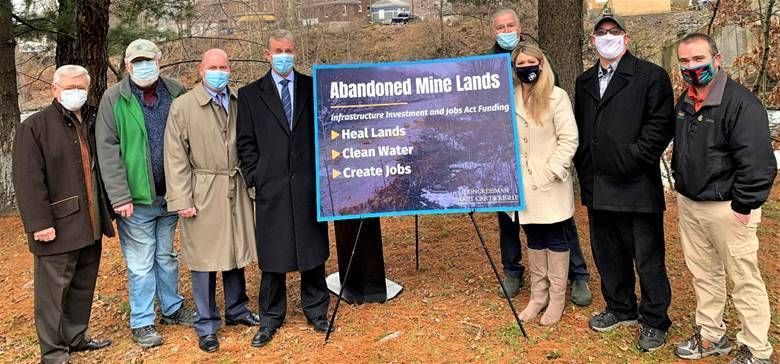 A group of people standing next to a sign

Description automatically generated with medium confidence